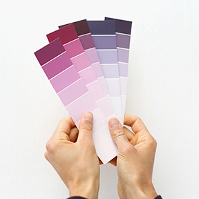man's hands holding color cards against a white wall